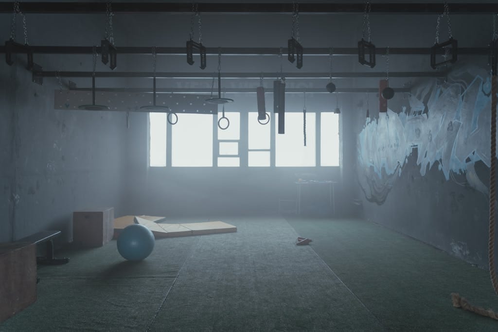 Empty industrial-style gym room with functional fitness equipment and natural lighting.