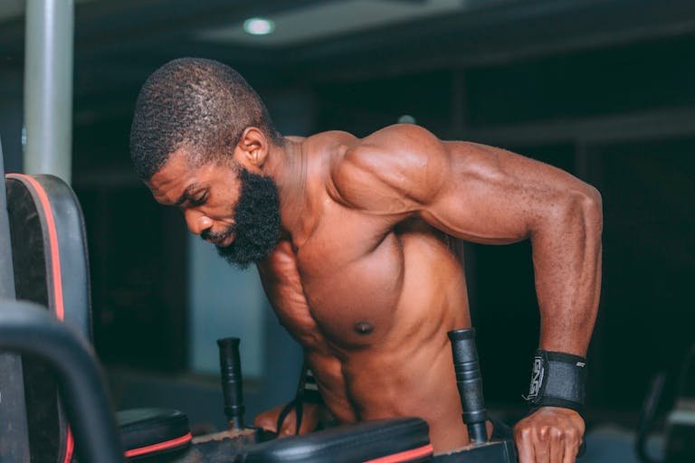 Muscular man doing tricep dips in a gym, Accra, Ghana. Strong fitness motivation.